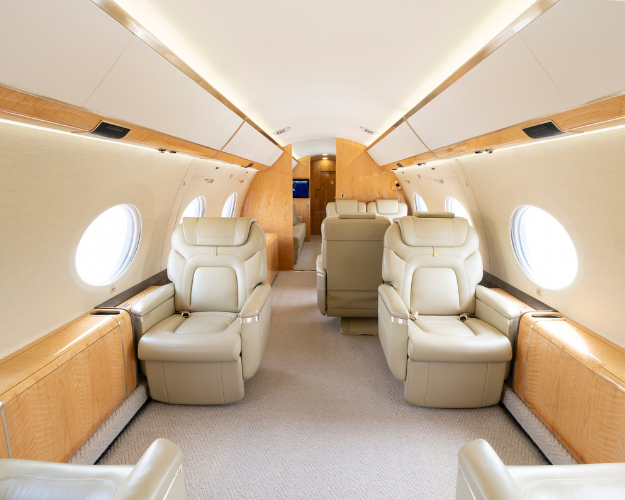 Elegant forward cabin of the 2014 Gulfstream G650ER with a four-place club seating arrangement and two-fold-out side ledge tables for meetings or leisure.