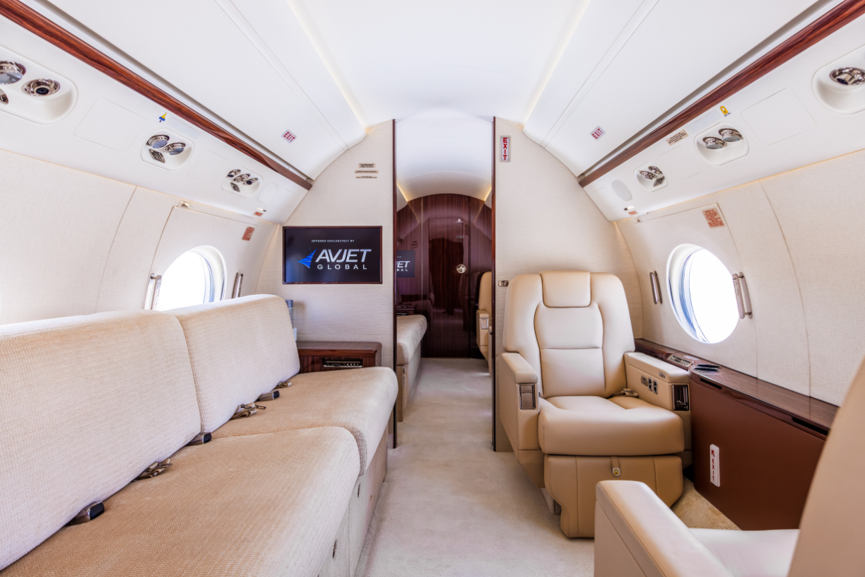 Mid-section view of the Gulfstream G550 cabin, showcasing a comfortable couch and two chairs in a stylish and spacious setting.