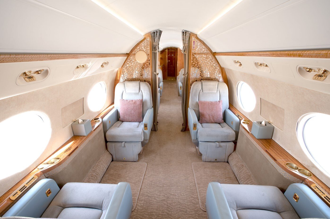 The forward cabin of this 2010 Gulfstream G550 offers a serene and refined atmosphere with four wide leather club seats, elegant wood accents, and gold-finished details. Large oval windows illuminate the space, creating a bright, comfortable setting for both business and relaxation.