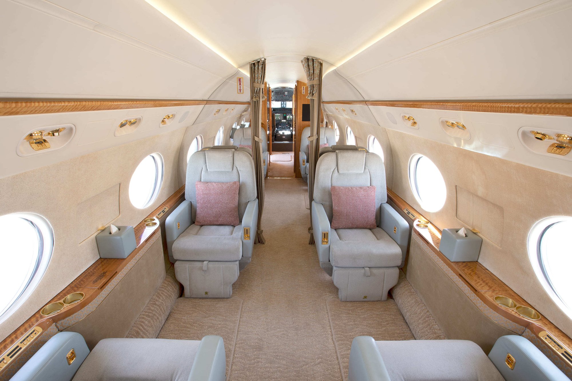 The mid cabin of this 2010 Gulfstream G550 is designed for sophistication and comfort, featuring four plush leather club seats with gold-accented details and warm wood finishes. Large oval windows fill the cabin with natural light, creating a bright, elegant space ideal for both productivity and relaxation on long-range flights.