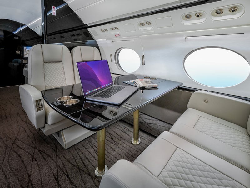 Luxury interior of private jet with a computer on top of a desk