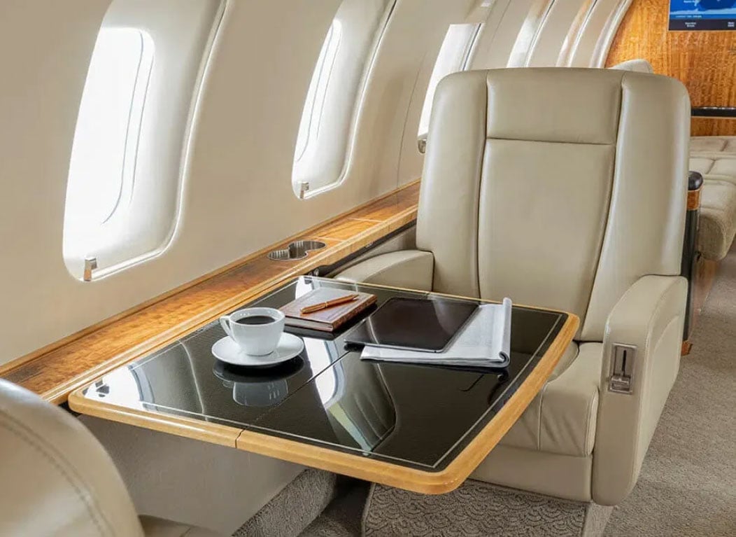 Interior of Bombardier aircraft, including a plush leather chair and desk