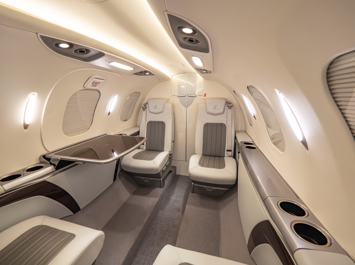 2022 HondaJet Elite S mid-cabin interior showing a refined light jet layout with executive leather seating, side tables, integrated storage, LED cabin lighting, and a quiet, modern cabin design.