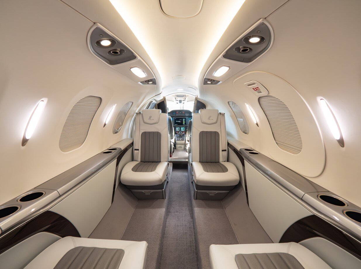 2022 HondaJet Elite S interior cabin featuring a modern light jet layout, premium leather club seating, spacious aisle, LED cabin lighting, and a forward view into the advanced cockpit.