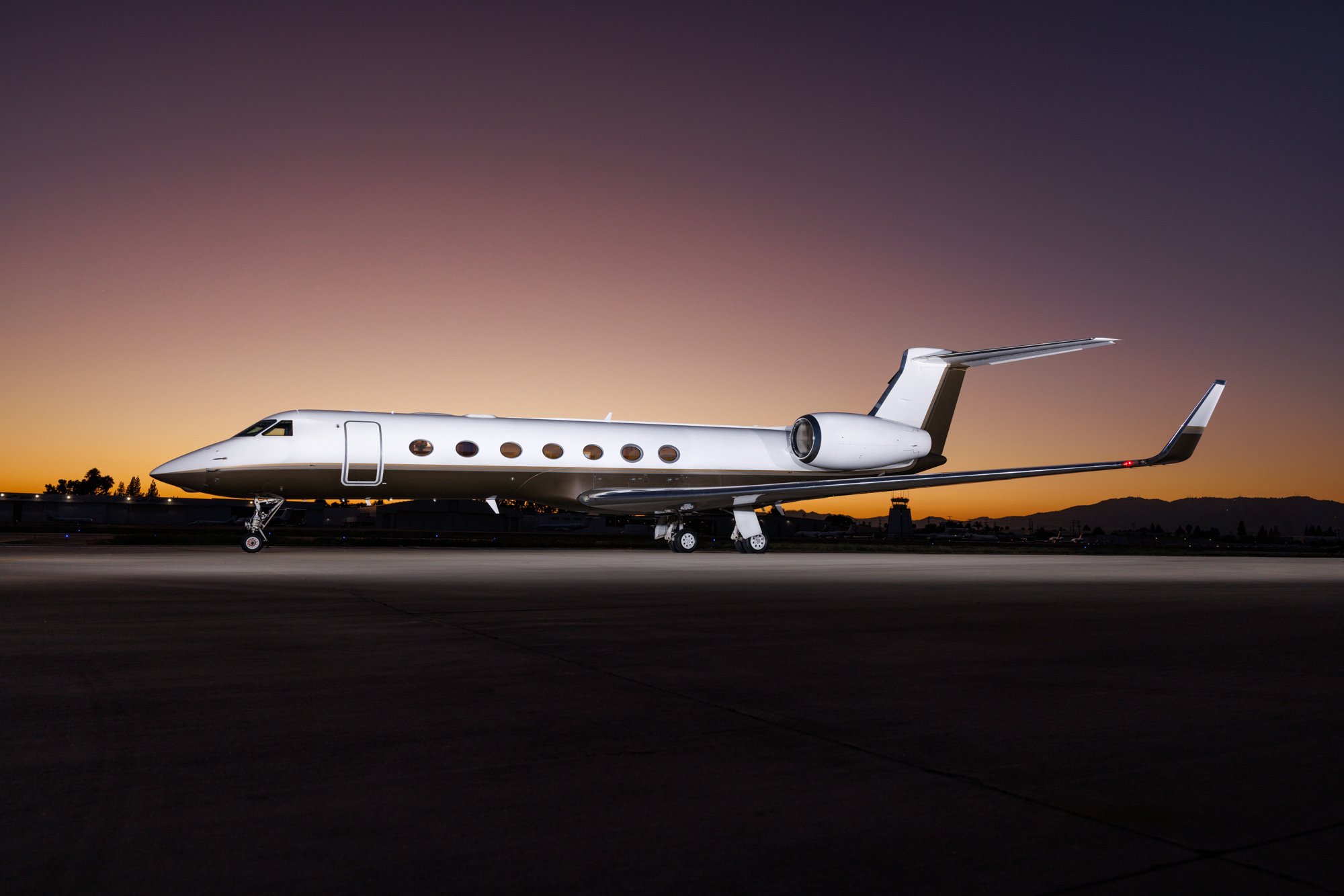 Exterior of a Gulfstream G550 private jet at sunset, highlighting its sleek design, ultra-long-range capability, and luxurious presence on the tarmac.