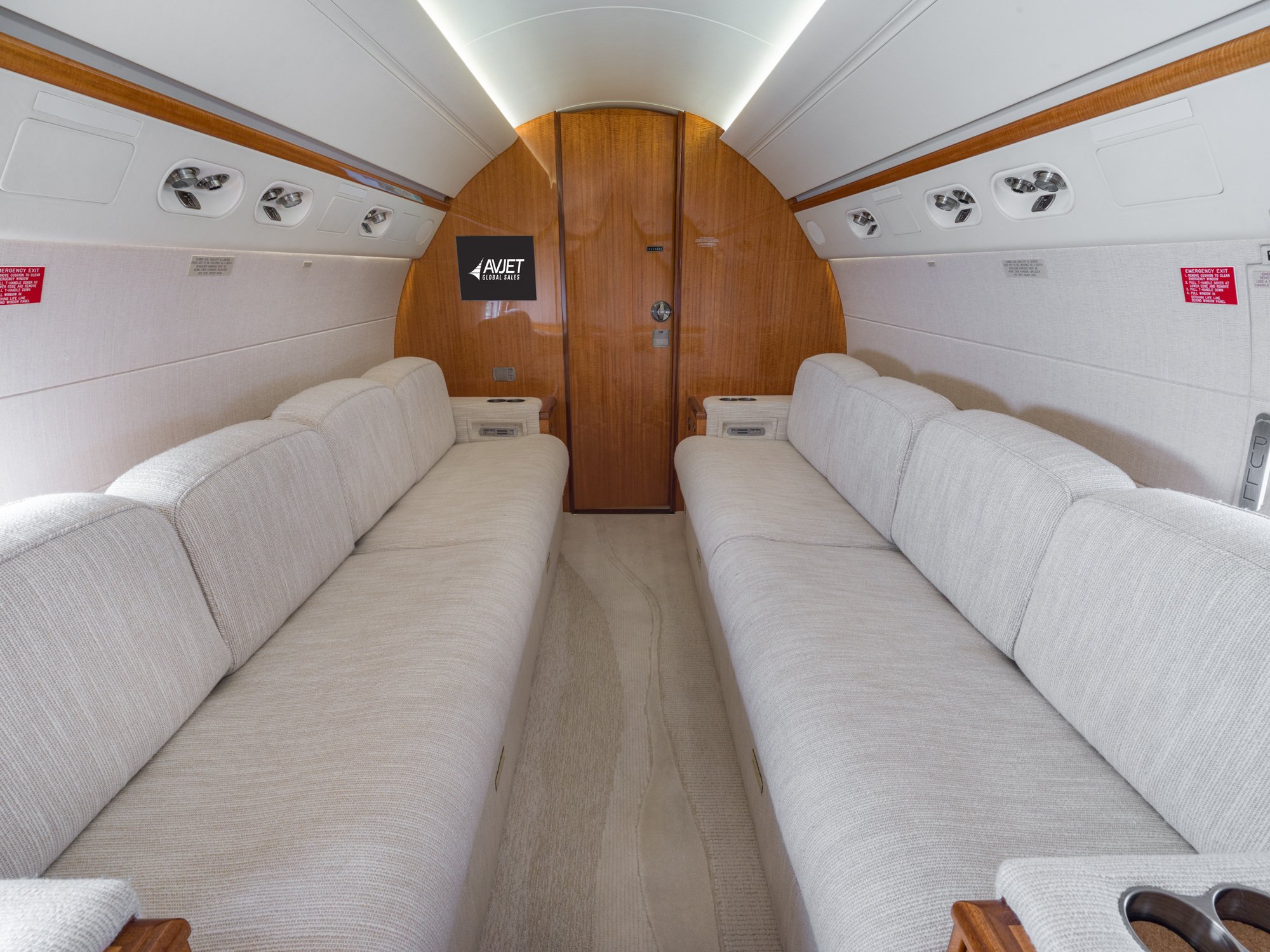 Aft cabin with dual opposing cream divans, soft textured upholstery, and wood-accented rear bulkhead in a Gulfstream G550.