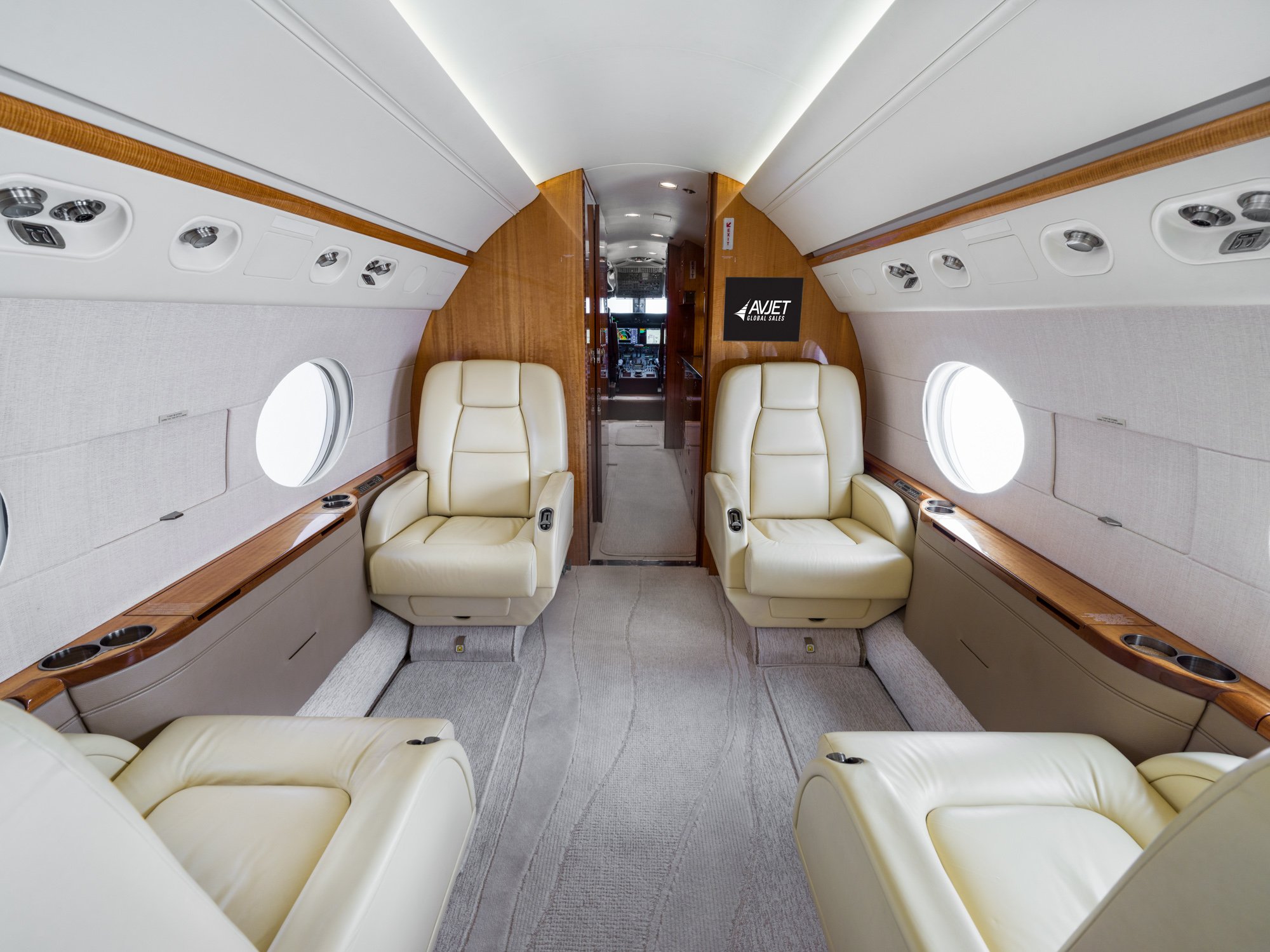 Forward Cabin, View Looking Forward Spacious four-seat club configuration with plush cream leather seats, refined wood accents, and ample natural light—offering a bright, quiet environment for productive or relaxing flight moments.