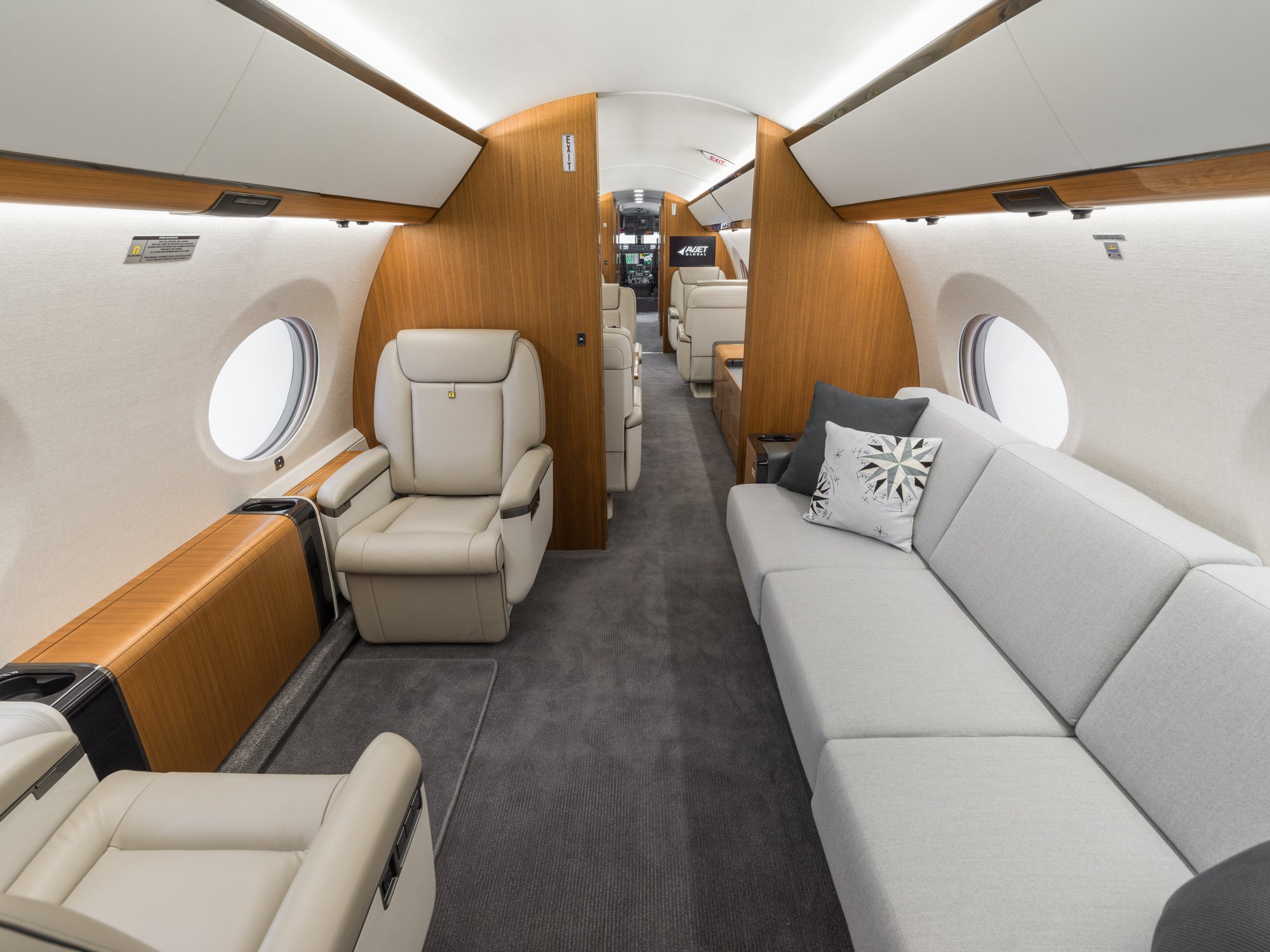 Aft cabin view of the Gulfstream 650ER looking forward, showcasing the spacious seating area with a three-seat couch and facing chairs, seamlessly connecting to the mid-cabin.