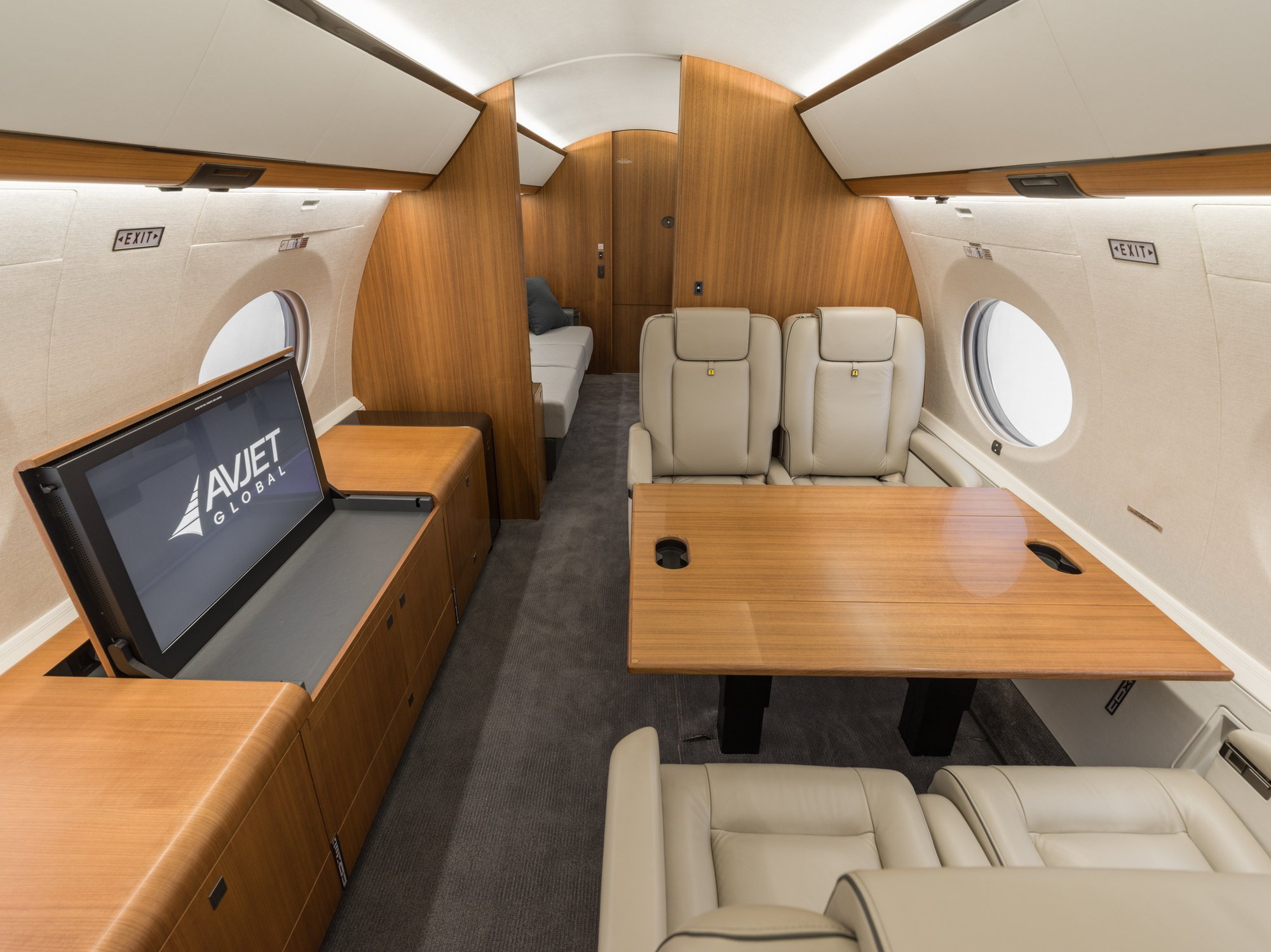 Forward cabin of the Gulfstream 650ER featuring plush chairs, a polished table, and an integrated TV, creating a sophisticated space for work or relaxation.