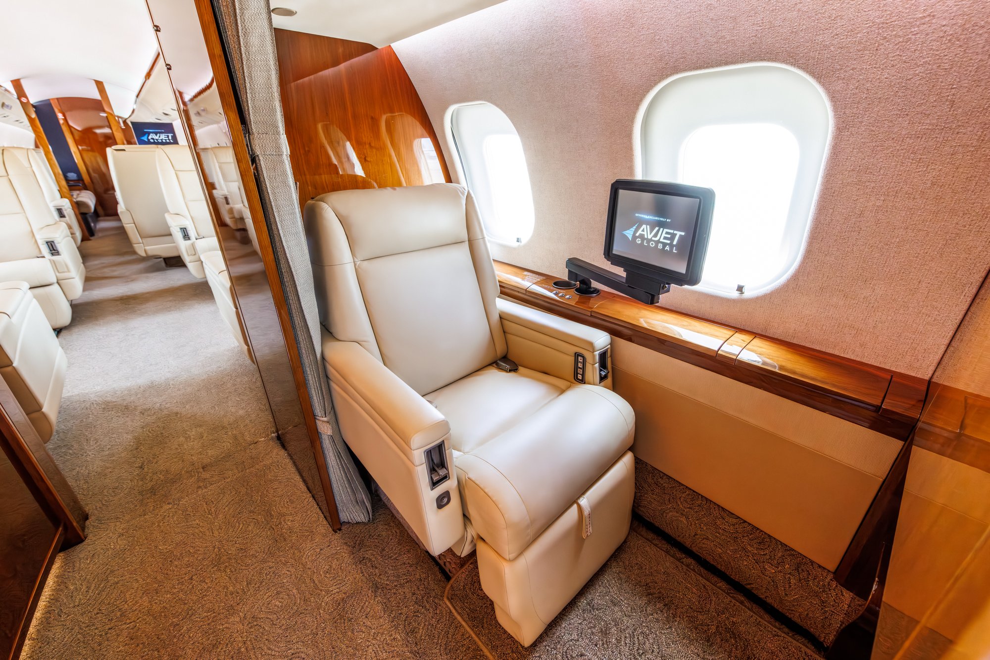 Interior view of the forward alley in a 2006 Bombardier Global XRS jet, featuring a seat with a monitor