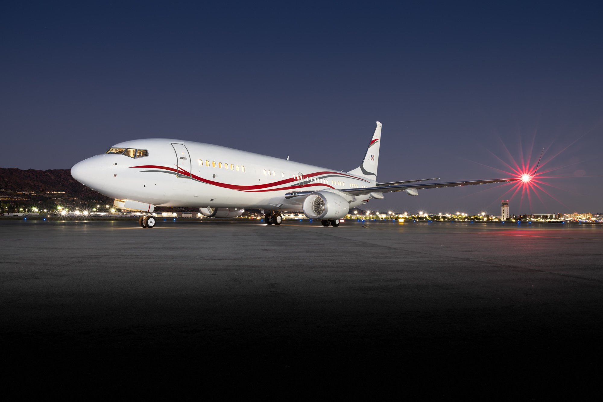 Full exterior view of a 2018 Boeing Business Jet 2 (BBJ2) featuring a custom white and red livery, showcasing the aircraft's complete profile and executive design.