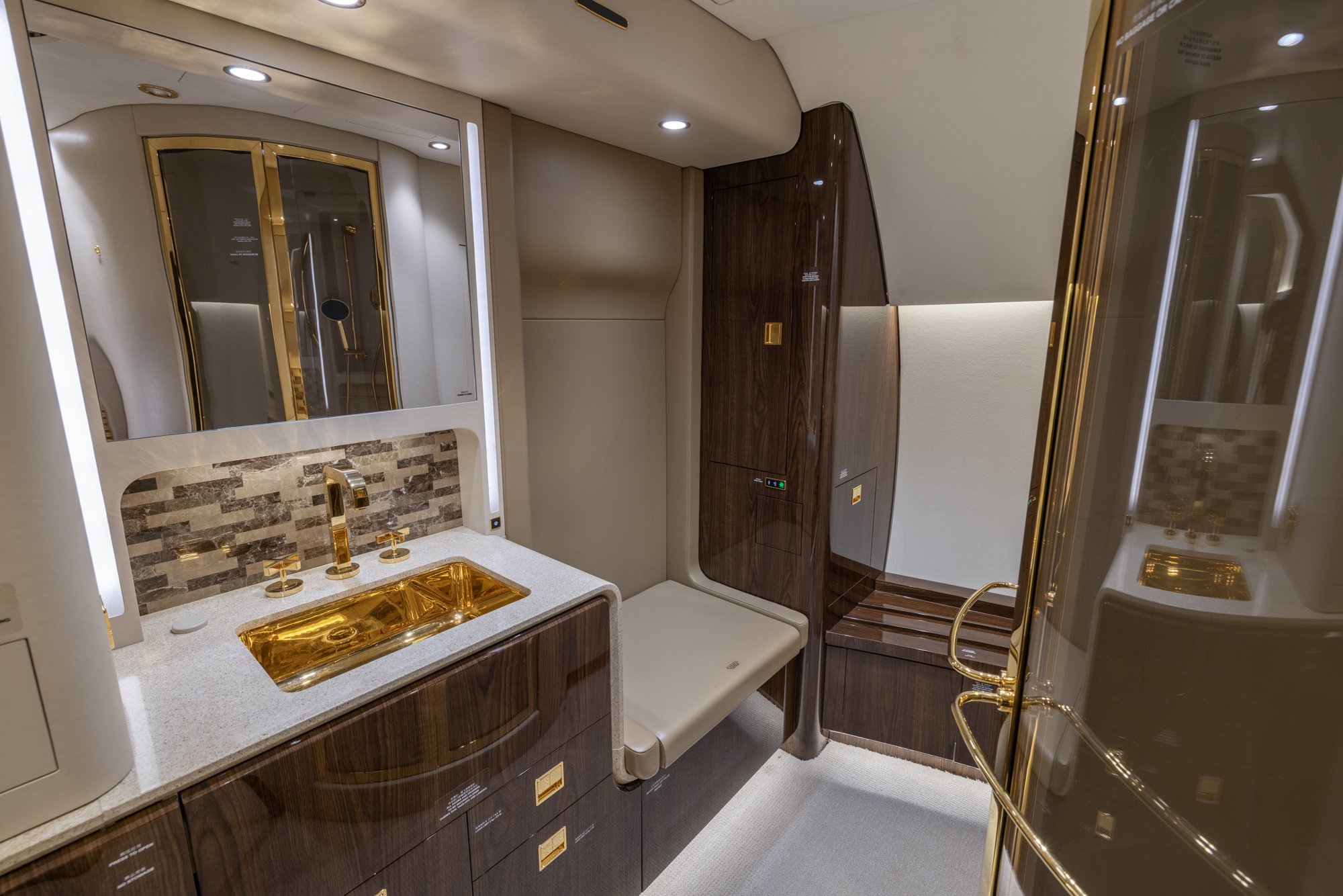 The VIP Lavatory aboard the 2018 Boeing Business Jet 2 (BBJ2) showcases exceptional craftsmanship with premium stone surfaces, rich wood cabinetry, gold-finished fixtures, and a spacious layout. Designed for maximum comfort and privacy, this elegant bathroom enhances the luxury private jet experience with refined style and executive-level amenities.