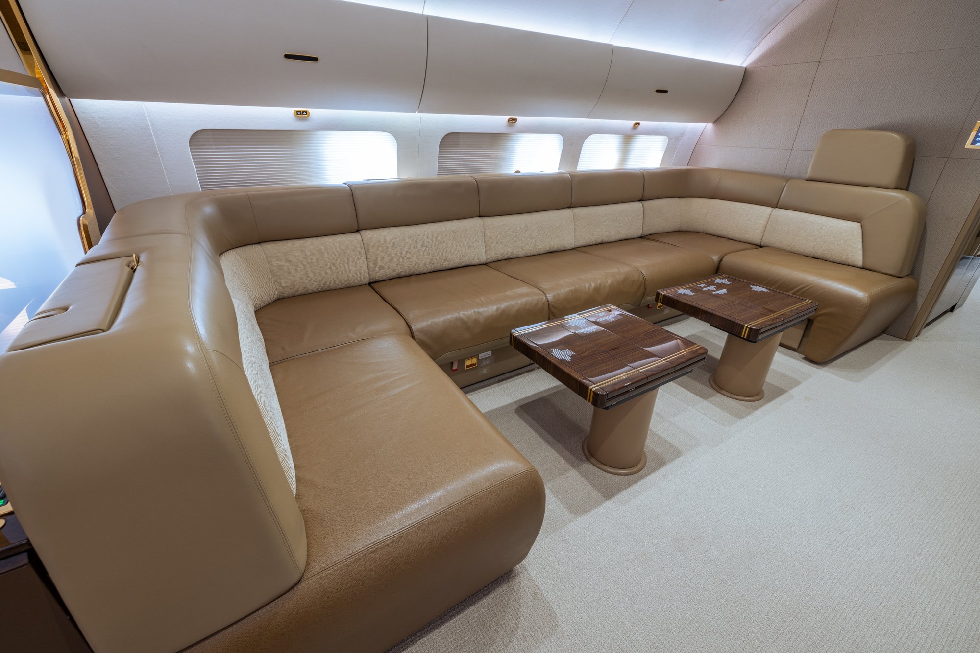 VIP Lounge with a spacious custom storage credenza, dual tables, premium finishes, and an open layout designed for comfort and in-flight entertainment aboard the BBJ2.