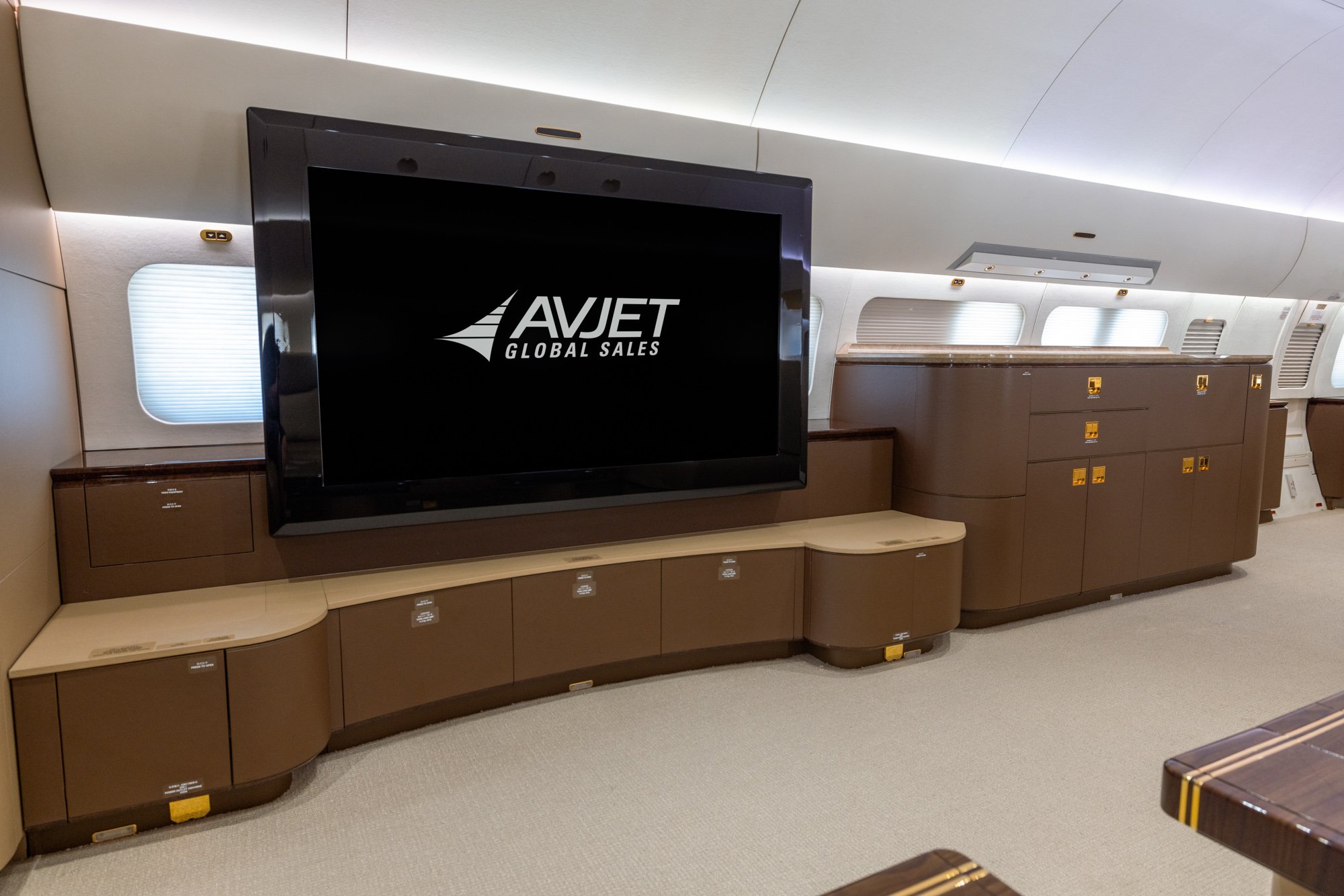 VIP Lounge entertainment area featuring a large-screen display, custom wood cabinetry, integrated storage drawers, and premium finishes aboard the 2018 Boeing Business Jet 2 (BBJ2).