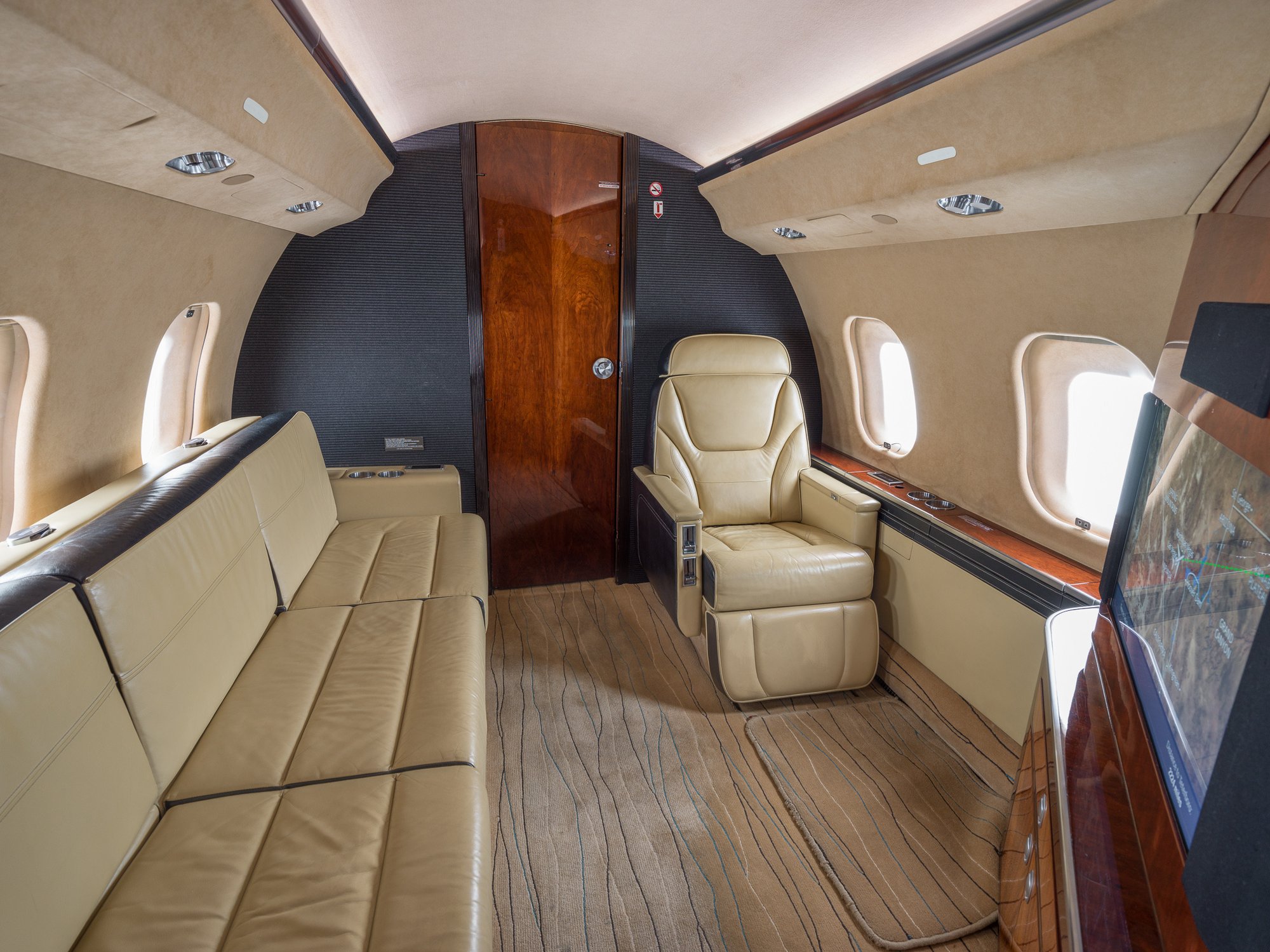 Aft cabin view of the 2007 Bombardier Global XRS looking aft, highlighting the comfortable three-seat divan and elegant interior design, offering a luxurious in-flight experience.