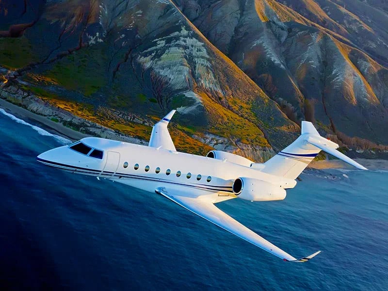 Private jet flying near a coastline over water