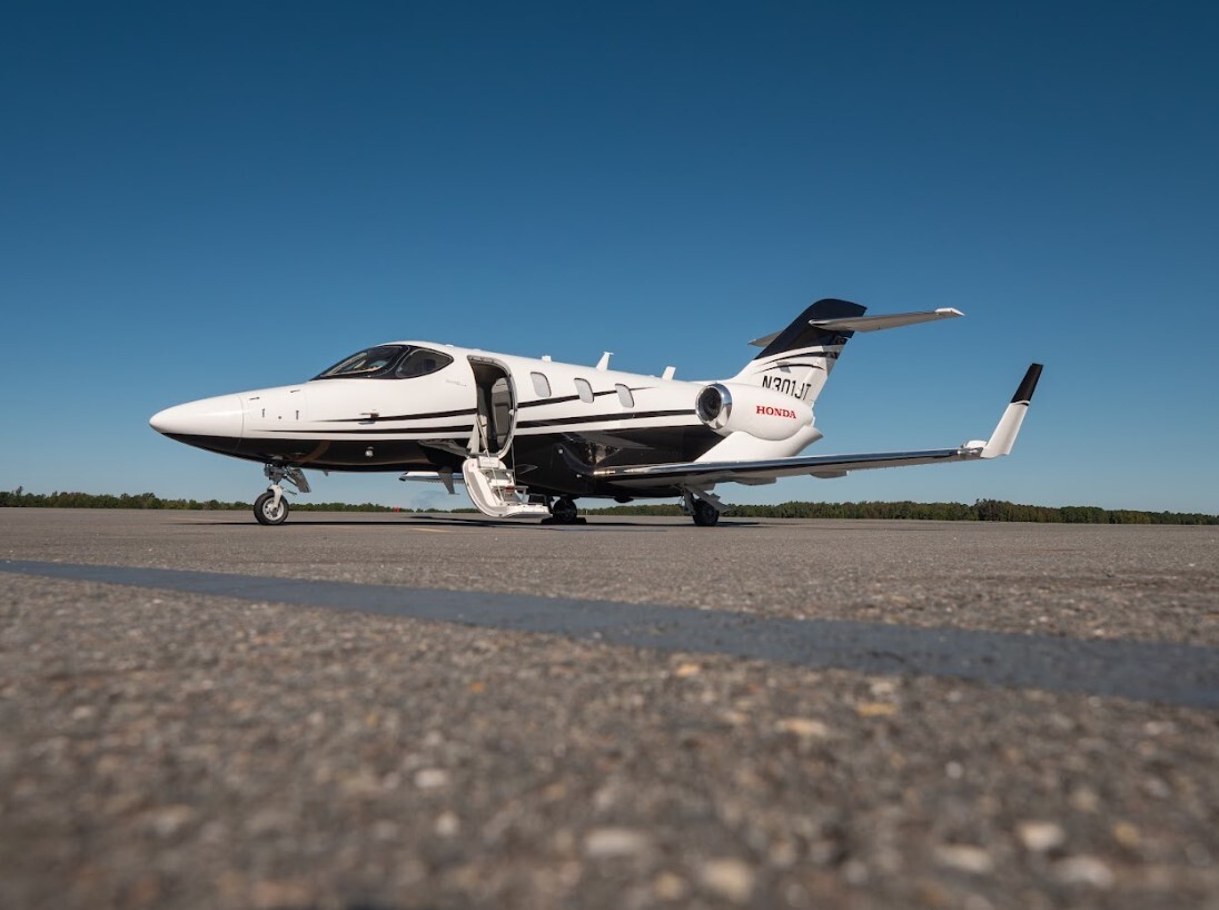 2022 HondaJet Elite S exterior side profile parked on the runway, highlighting its sleek aerodynamic design, over-the-wing engines, open entry door, and modern light business jet configuration.