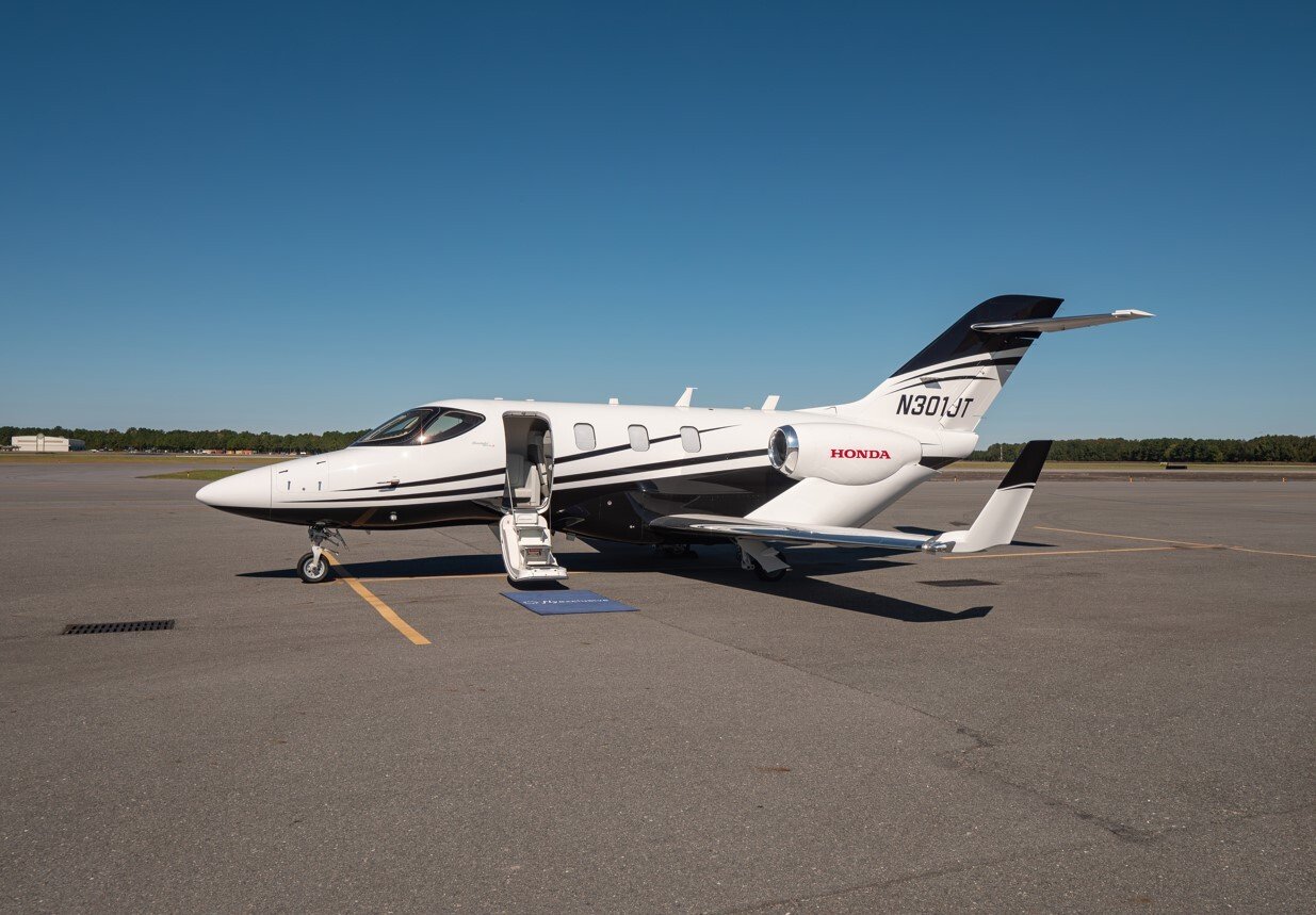 HondaJet HA-420 light business jet exterior, parked on airport tarmac, showcasing its sleek aerodynamic fuselage, over-the-wing engine configuration, and modern tail design.
