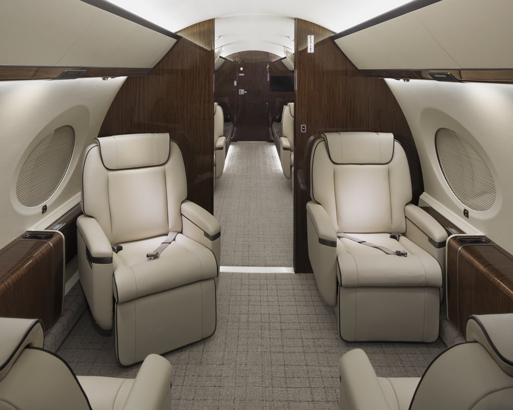 Interior of the 2016 Gulfstream G650ER showing the forward cabin with four plush, leather seats arranged in a four-place club configuration. The cabin features a modern, elegant design with ample space and high-end finishes, highlighting the jet's luxury and comfort.