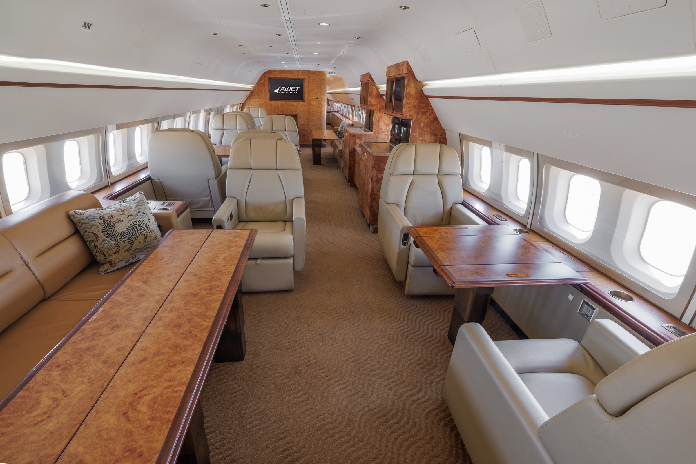 Spacious interior of a 2002 Boeing Business Jet 2 featuring luxurious leather seating, polished wood tables, and executive-style layout for private air travel.