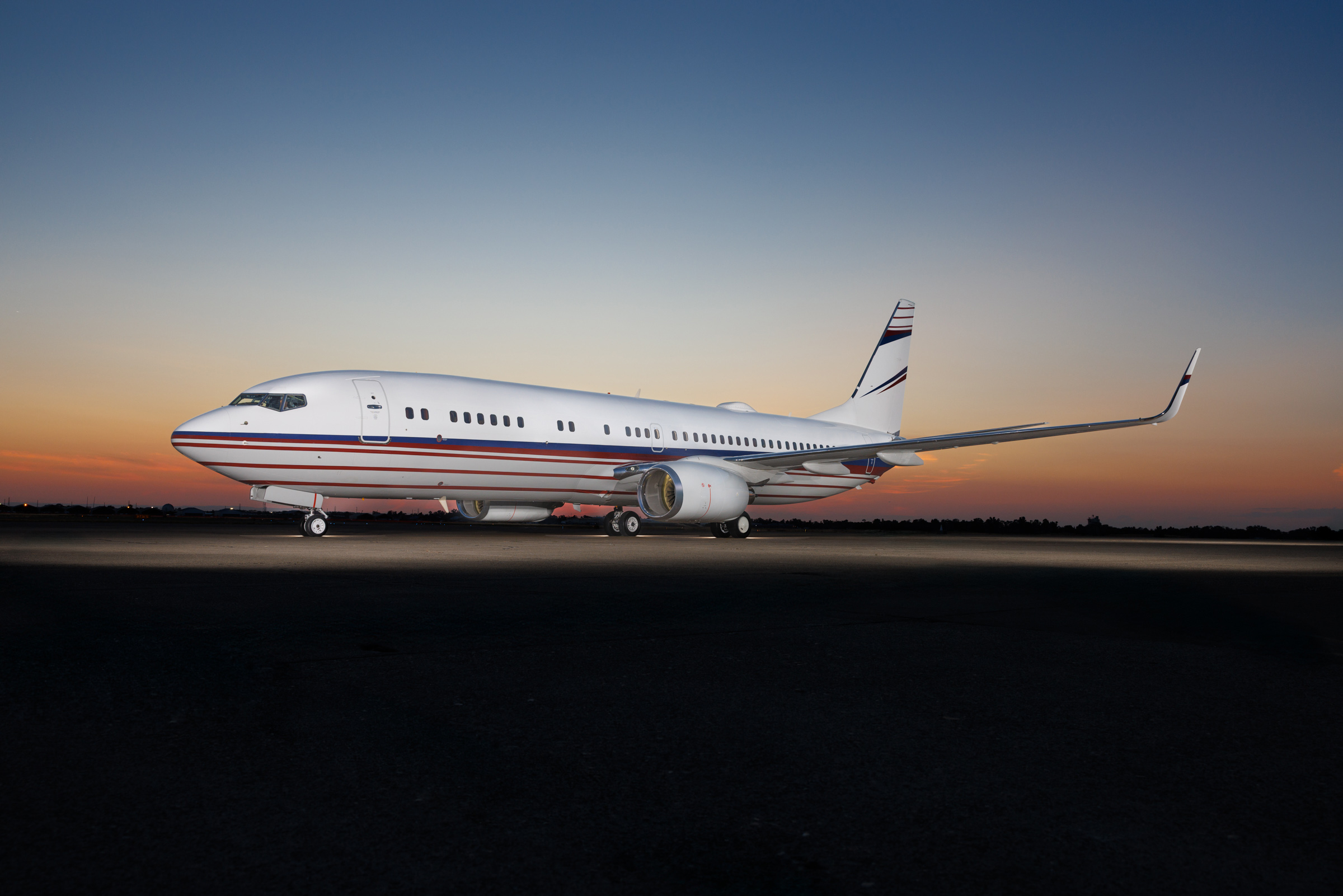 Private Boeing jet parked on runway at sunset, showcasing luxury and long-range capability.
